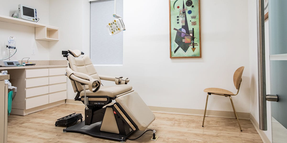 dental exam room with beige chair and abstract art on wall